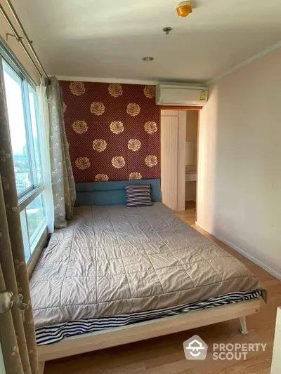 Cozy bedroom with floral accent wall and large window in modern apartment