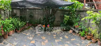 Charming garden patio with lush potted plants and stone tile flooring, perfect for relaxation.