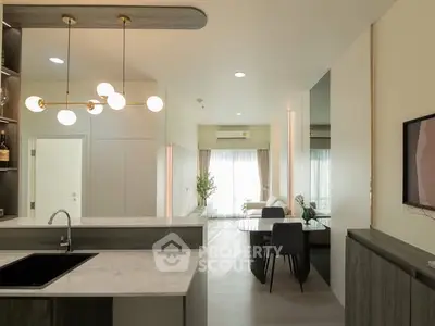 Modern open-layout kitchen and living room with elegant lighting and stylish decor.