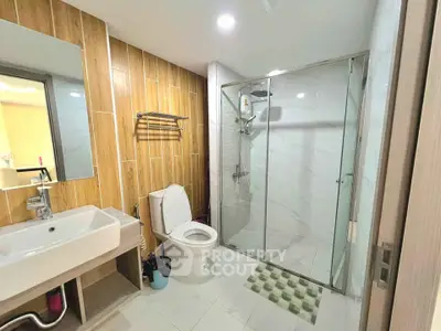 Modern bathroom with glass shower and wooden accents in a stylish apartment.