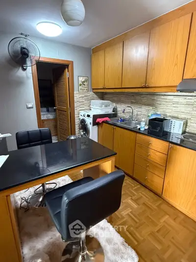 Cozy kitchen with wooden cabinets, modern appliances, and a washing machine, perfect for urban living.