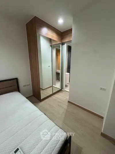Modern bedroom with mirrored closet and ensuite bathroom in stylish apartment.