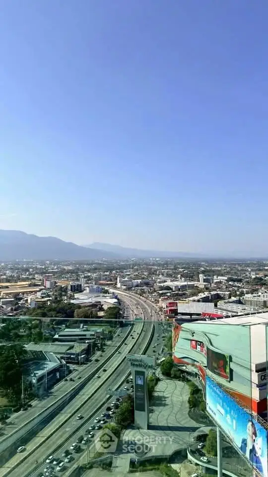 Stunning cityscape view from a high-rise building showcasing urban landscape and distant mountains.