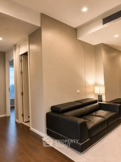 Modern living room with sleek black leather sofa and warm lighting