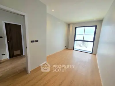 Spacious empty room with wooden flooring and large window, perfect for customization.