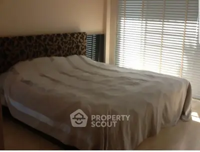 Spacious bedroom with large bed and natural light from window blinds.