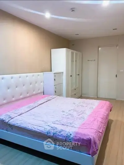 Spacious bedroom with elegant white furniture and cozy pink bedding, perfect for relaxation.
