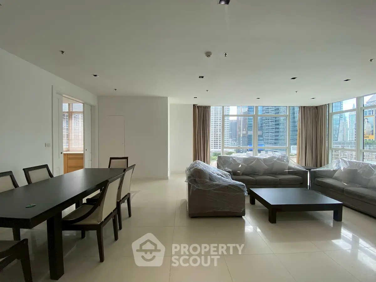 Spacious modern living room with city view, elegant dining area, and large windows for natural light.