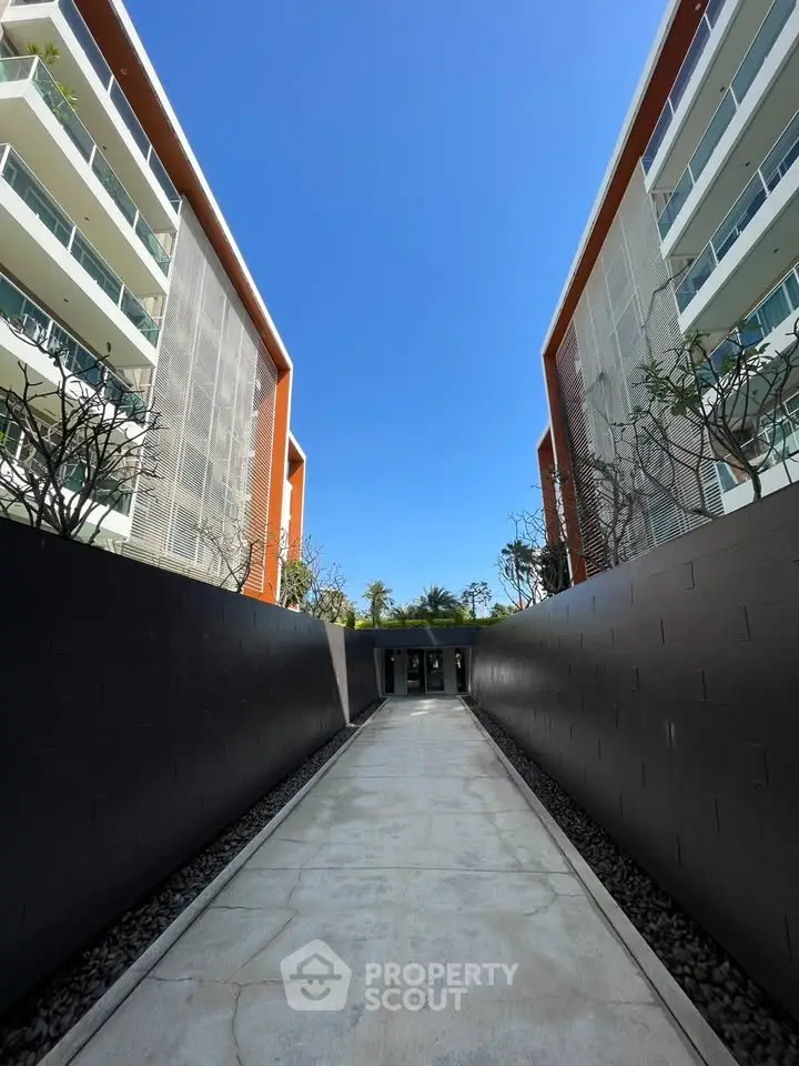 Modern apartment building entrance with sleek design and clear blue sky