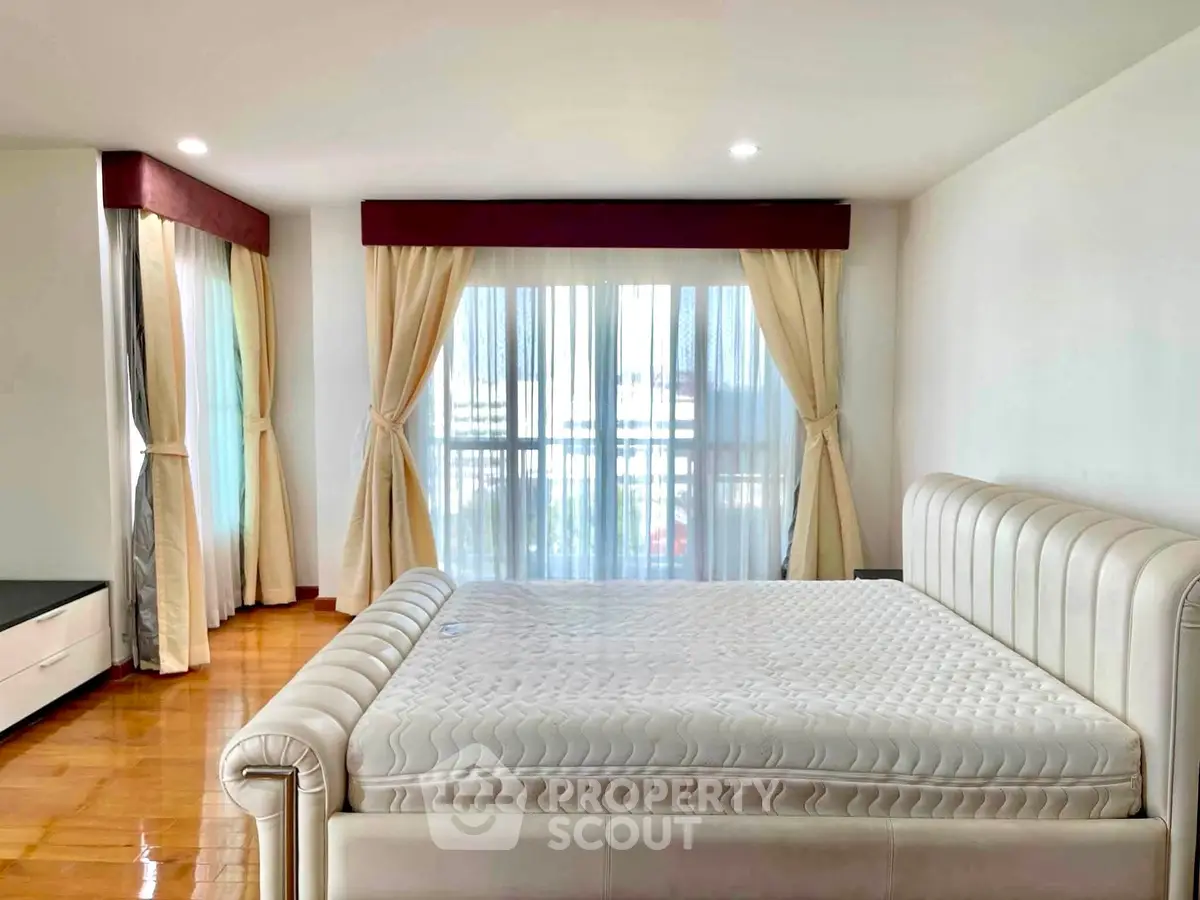 Spacious bedroom with elegant curtains and luxurious bed in modern apartment