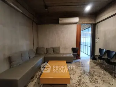 Modern industrial-style living room with concrete walls and minimalist furniture.