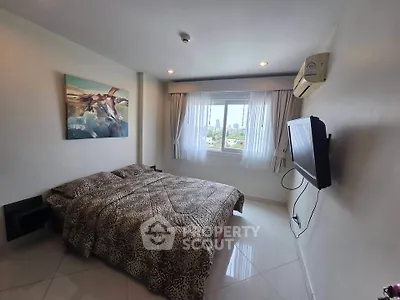 Spacious bedroom with city view, modern decor, and wall-mounted TV in a stylish apartment.