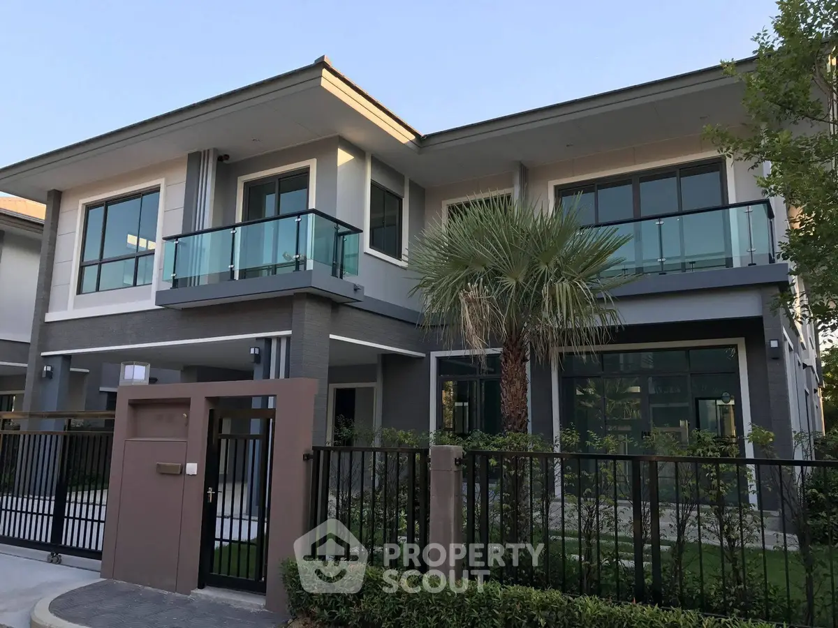 Modern two-story house with glass balconies and lush landscaping
