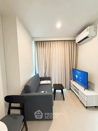 Modern living room with sleek furniture and natural light, featuring a cozy sofa and flat-screen TV.