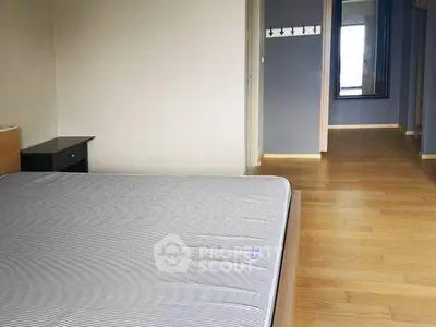 Spacious bedroom with wooden flooring and ample natural light.