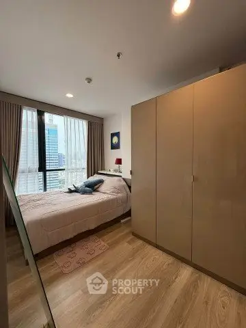 Modern bedroom with city view, featuring sleek wardrobe and cozy decor.