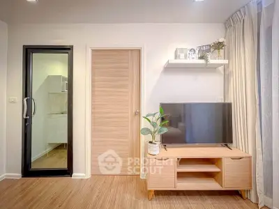 Modern living room with sleek TV stand and glass door leading to kitchen