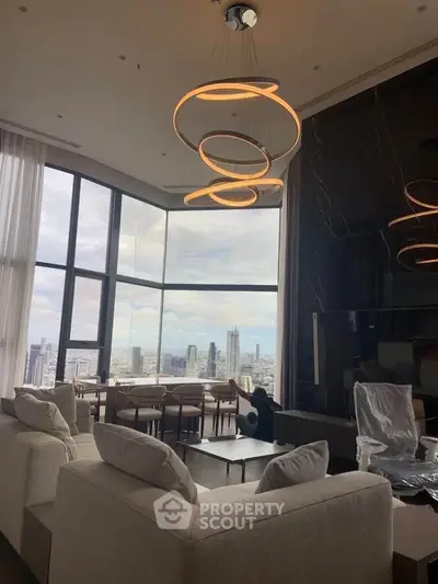 Luxurious living room with panoramic city view and modern lighting in high-rise apartment.