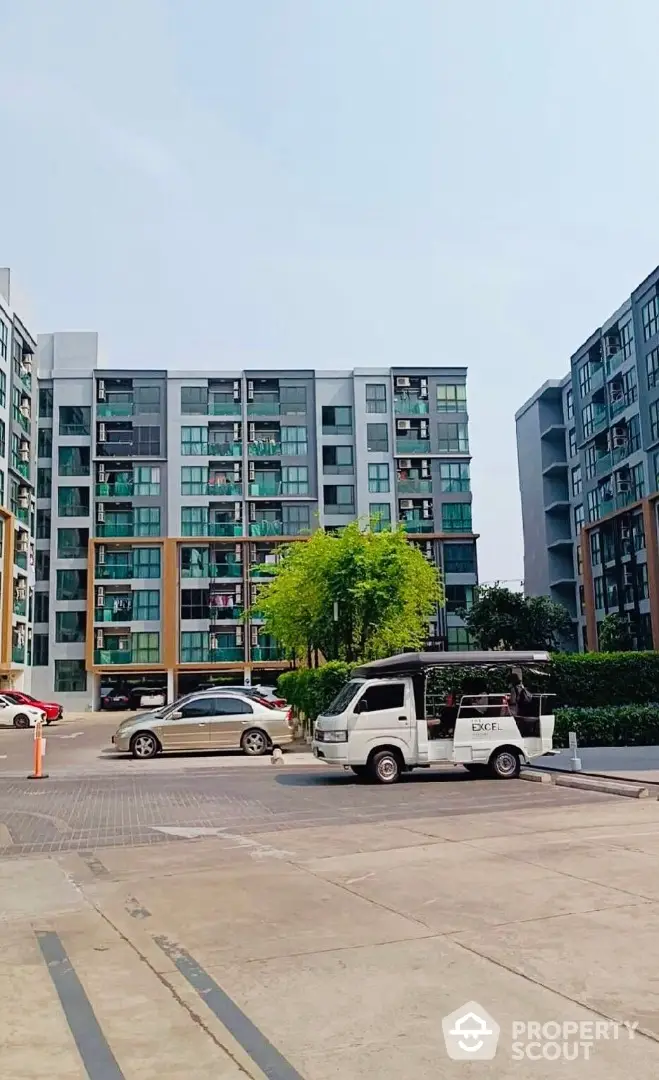 Modern apartment complex exterior with parking area and lush greenery