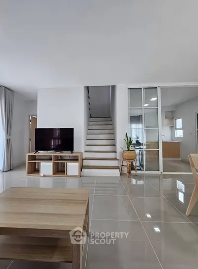 Modern living room with sleek staircase and open kitchen layout