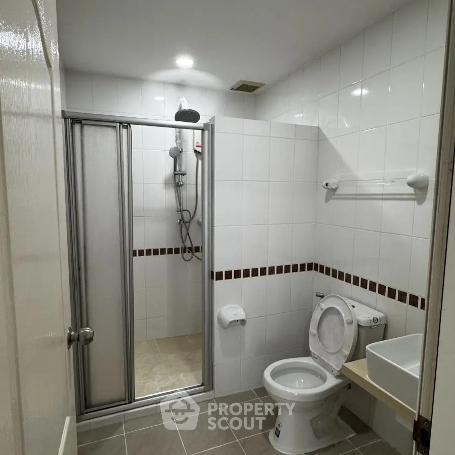 Modern bathroom with shower and toilet in a tiled setting