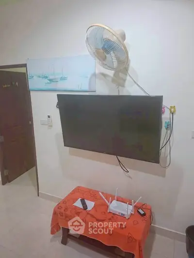 Cozy living room corner with wall-mounted TV and fan, perfect for relaxation.