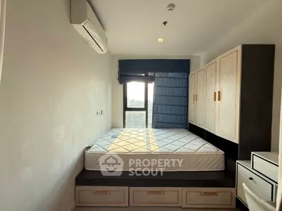 Modern bedroom with built-in storage and large window offering natural light.