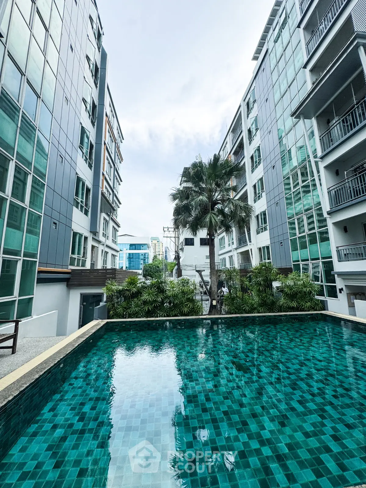 Modern apartment complex with a luxurious swimming pool and lush greenery.