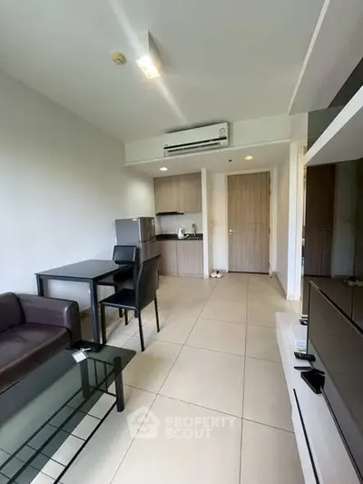 Modern apartment living room with sleek furniture and compact kitchen area.