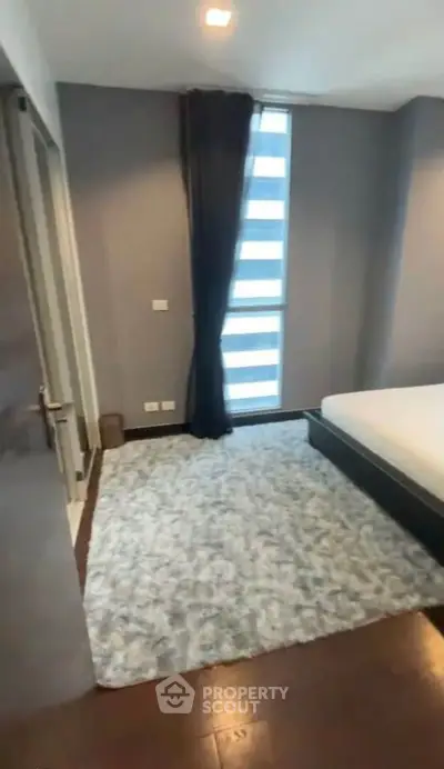 Modern bedroom with plush carpet and large window in stylish apartment