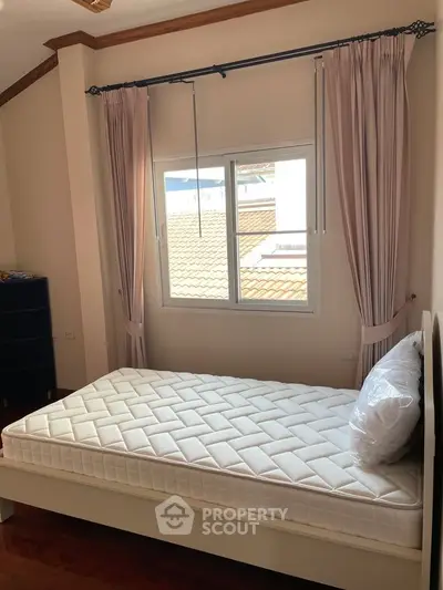 Cozy bedroom with natural light and elegant curtains, perfect for relaxation and comfort.