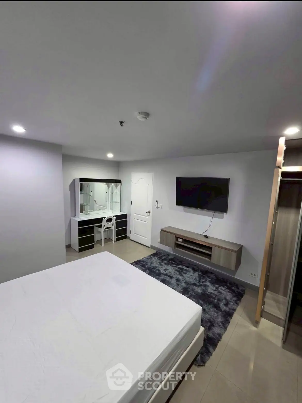 Modern bedroom with sleek furniture and wall-mounted TV in a stylish apartment.