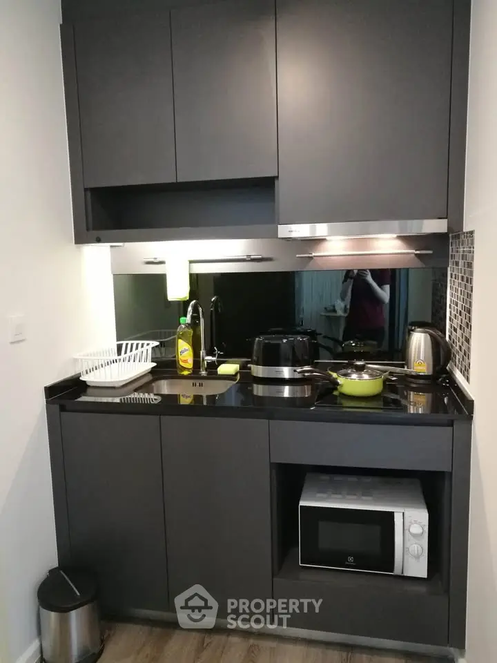 Modern compact kitchen with sleek black cabinets and appliances