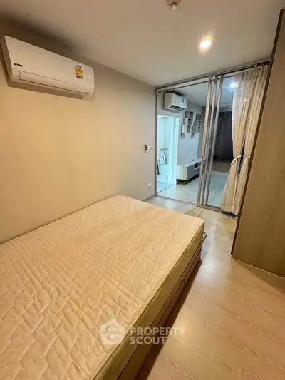 Modern bedroom with air conditioning and sliding glass doors leading to a living area.
