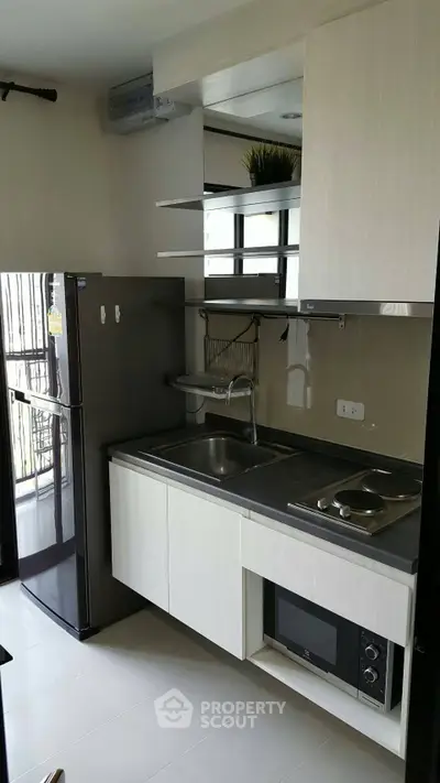 Modern compact kitchen with sleek cabinetry and appliances in a stylish apartment.
