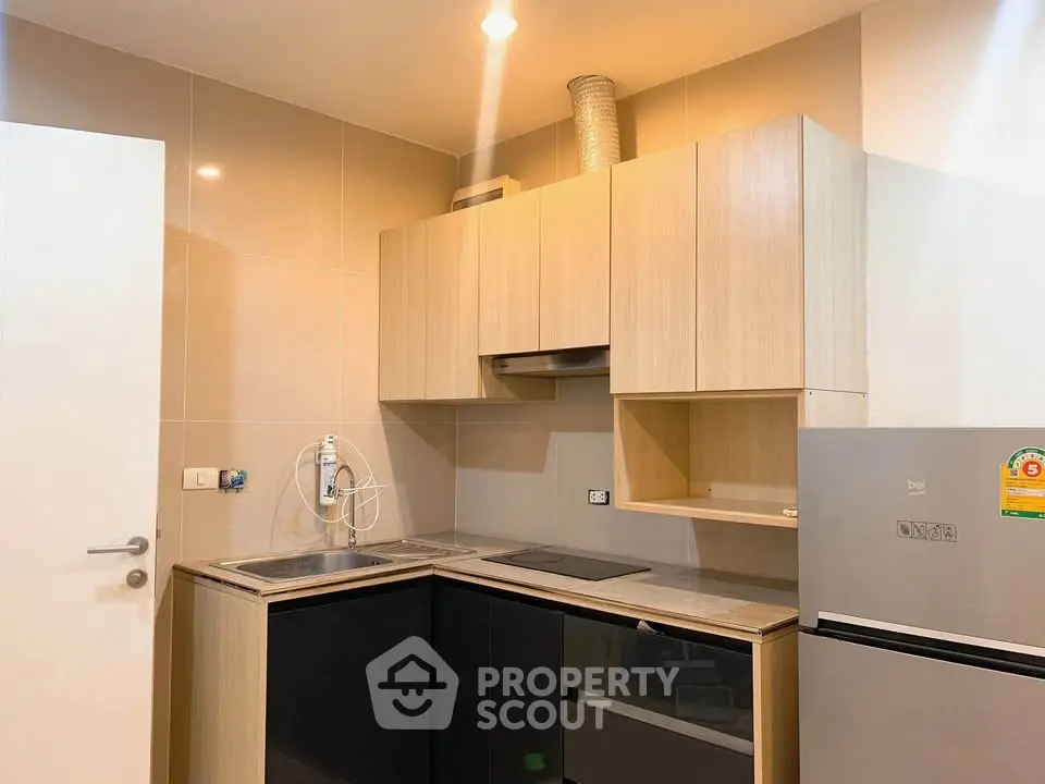 Modern kitchen with sleek cabinetry and stainless steel appliances in a cozy apartment.
