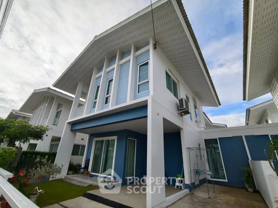 Modern two-story house with unique roof design and spacious outdoor area in a serene neighborhood.