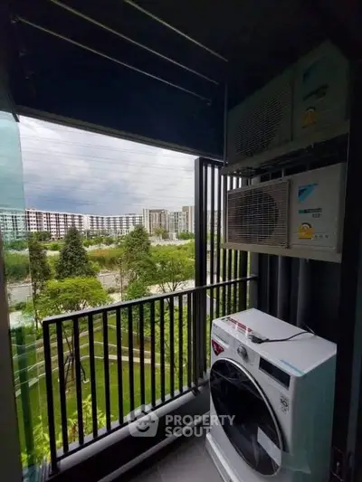 Modern balcony with washing machine and scenic view of lush greenery and buildings.