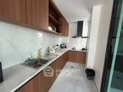 Modern kitchen with sleek wooden cabinets and marble backsplash in a contemporary apartment.