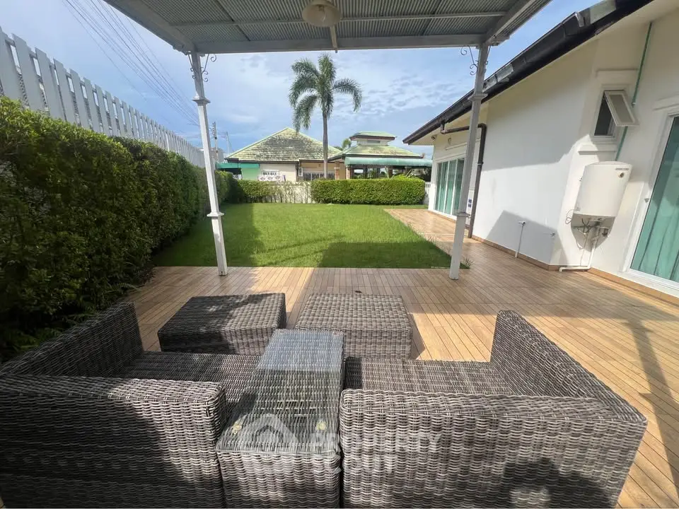 Charming outdoor patio with wicker furniture and lush green lawn in a serene residential setting.