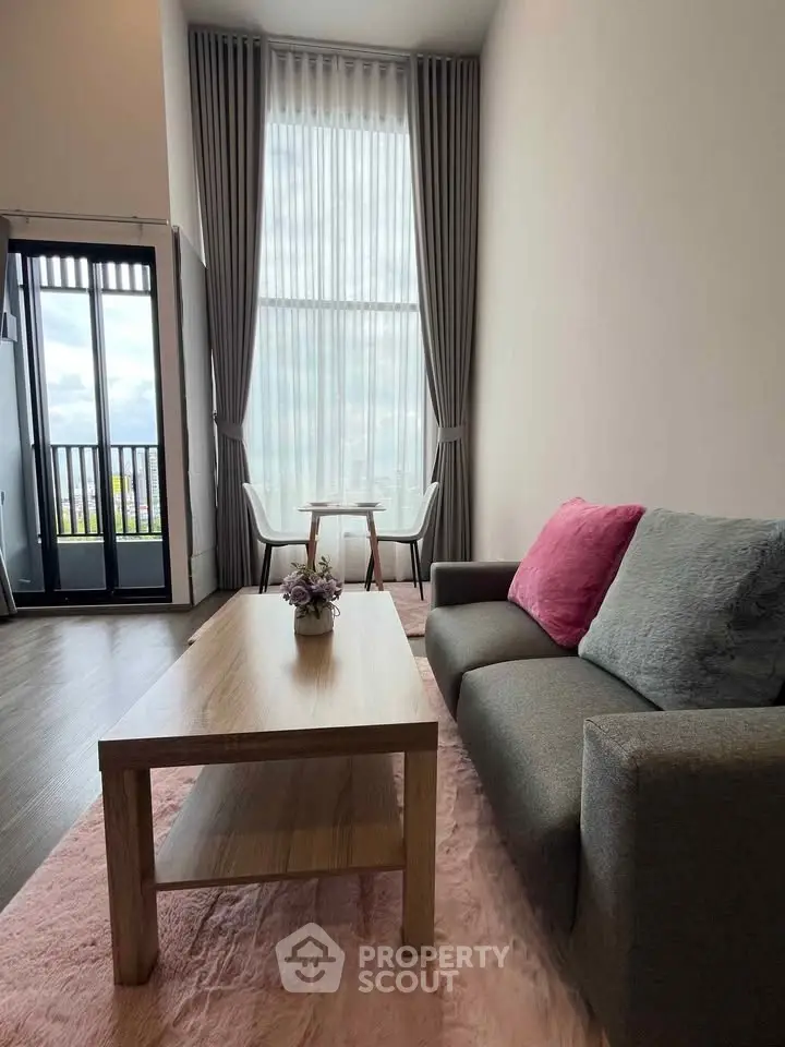 Modern living room with high ceilings, large windows, and stylish decor in a luxury apartment.