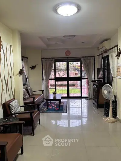 Spacious living room with elegant decor and garden view, perfect for family gatherings.