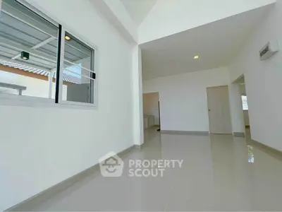 Spacious modern interior with high ceilings and sleek tile flooring, perfect for contemporary living.