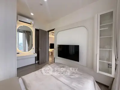 Modern bedroom with stylish decor and wall-mounted TV, featuring a glimpse into a luxurious bathroom.