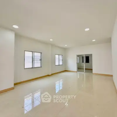 Spacious and bright living room with large windows and glossy tiled floors, perfect for modern living.