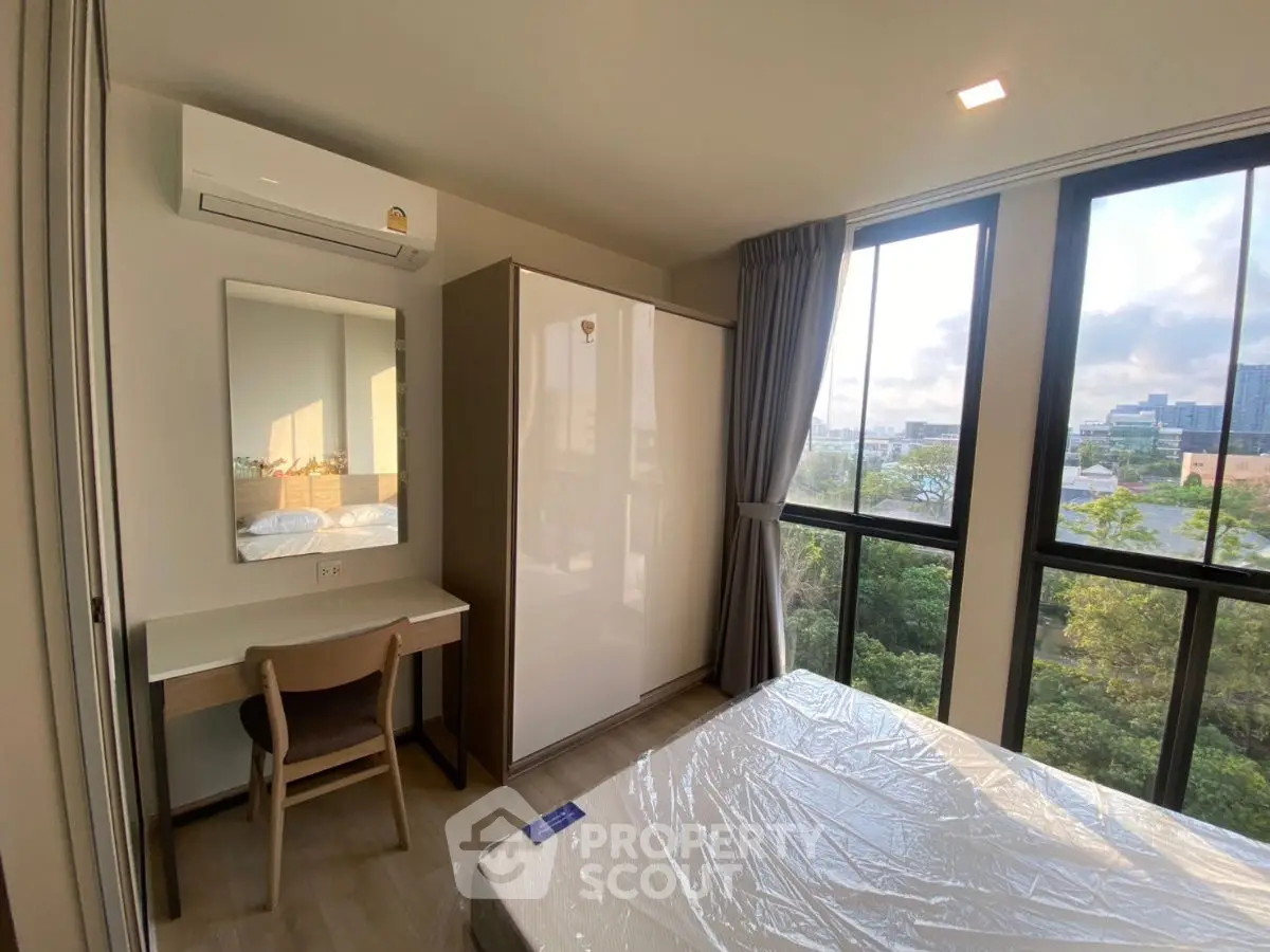 Modern bedroom with large windows and natural light, featuring a desk and wardrobe.