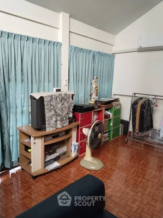 Cozy living room with vintage TV and fan, colorful storage, and air conditioning.