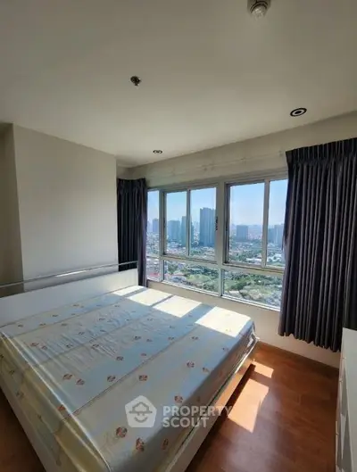 Spacious bedroom with large windows offering stunning city views, perfect for urban living.