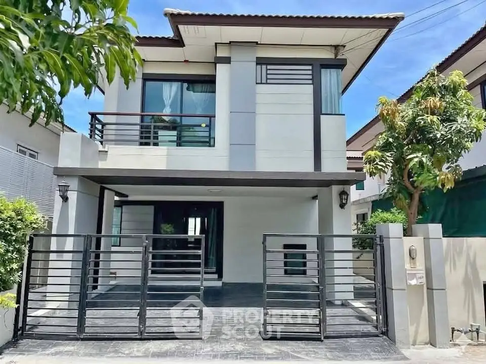 Modern two-story house with sleek design and gated driveway in a suburban neighborhood.