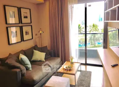 Cozy living room with modern decor and balcony view of lush greenery.